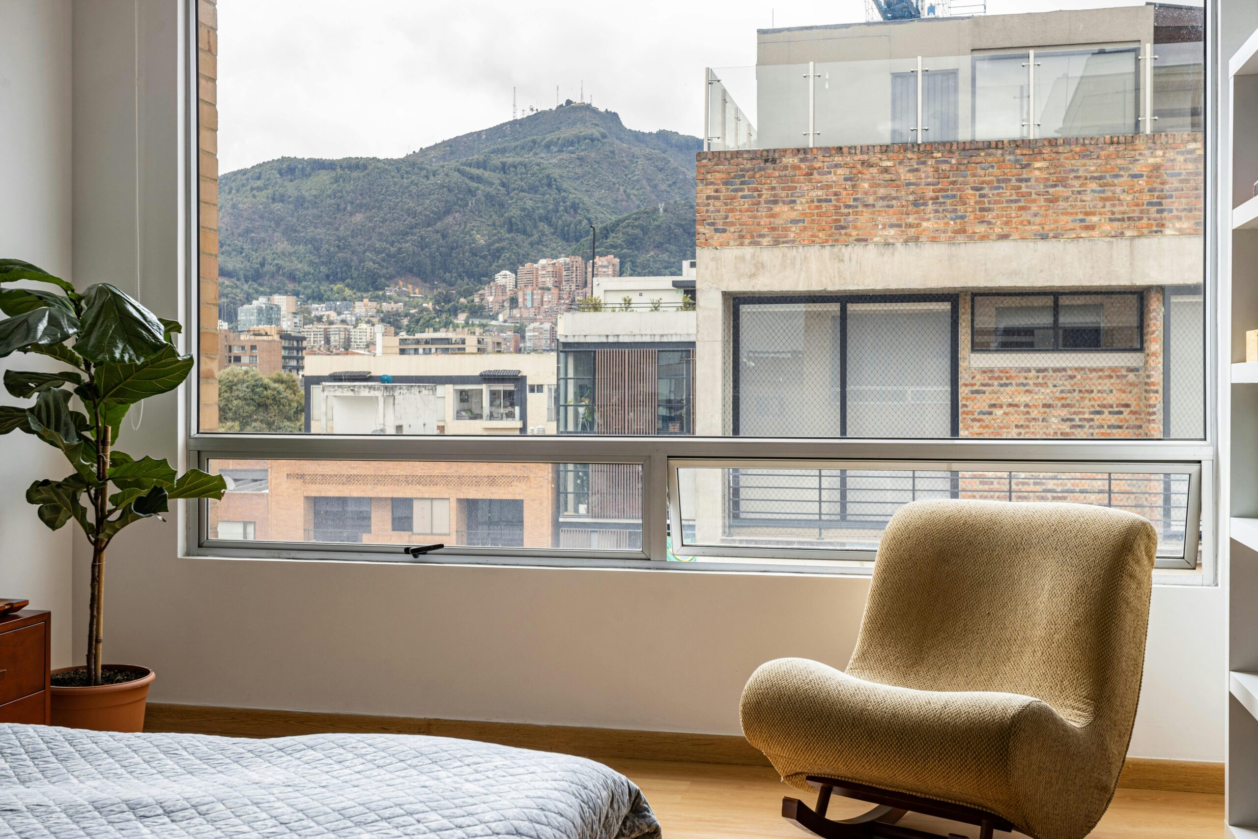 Stylish apartment interior in Bogotá with a cozy chair and mountain view.